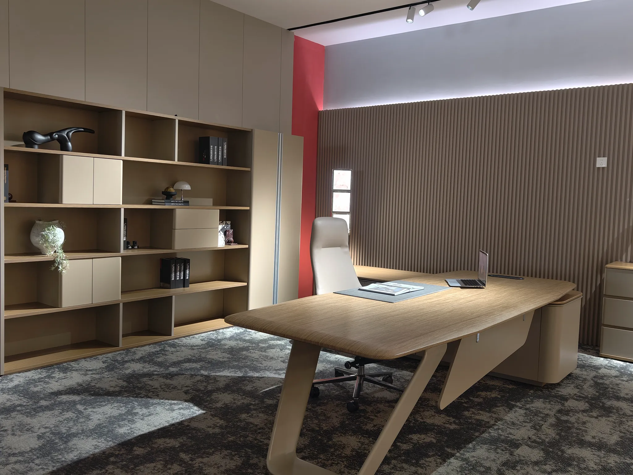 Wood-toned executive desk with angled supports and coordinating shelving in the FENLERN showroom