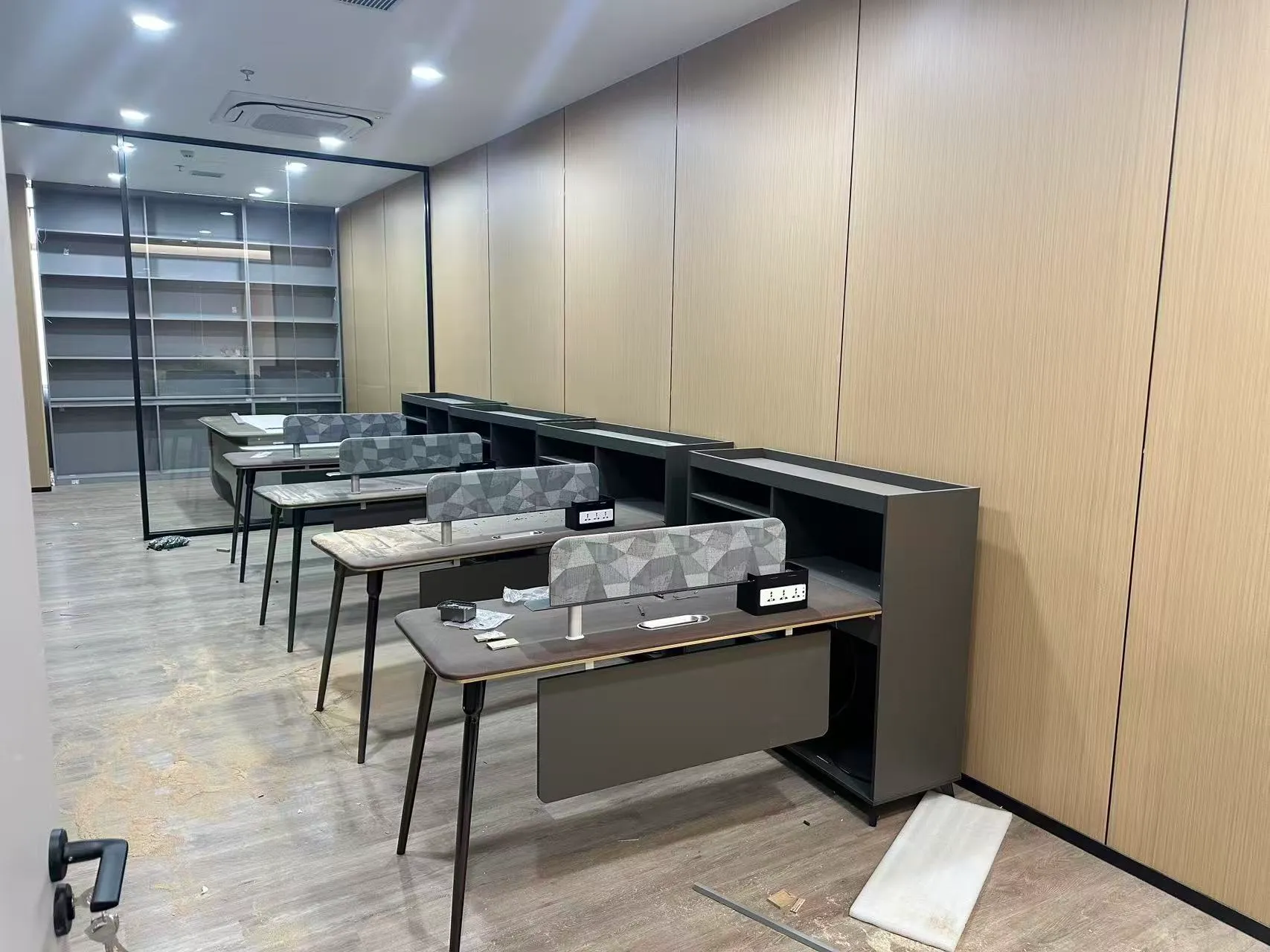 Departmental desks with patterned screens, desktop power modules and tall side storage units.
